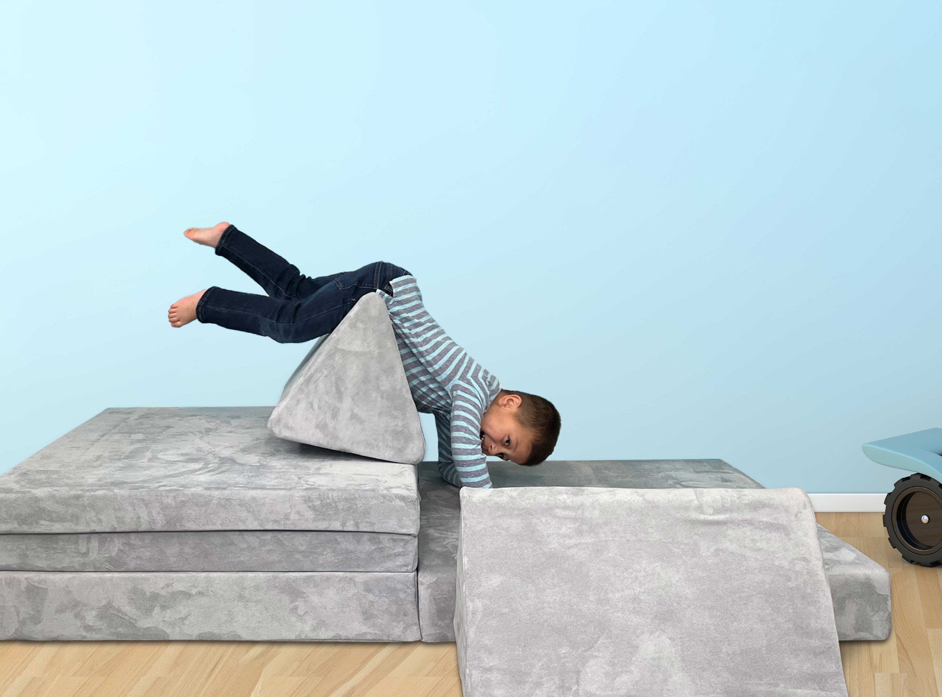 Young boy laughing and playing on Mod Blox 6-piece modular children's couch in gray microsuede.