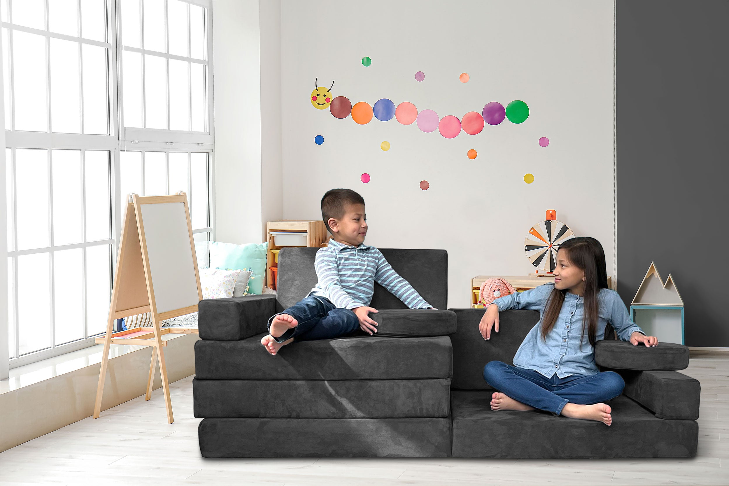 Young boy and girl interacting on gray Mod Blox 10-piece modular sofa with gray covers in a vibrant playroom setting.