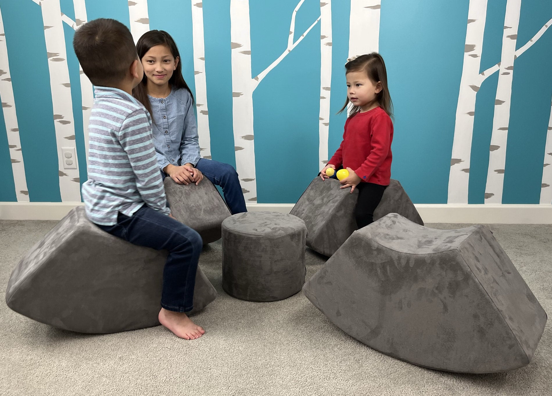 Children sitting on Mod Blox microsuede cylinder table and seats in a playful room.